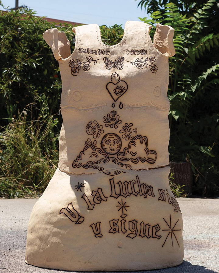 a clay statue of a dress with writings over it.